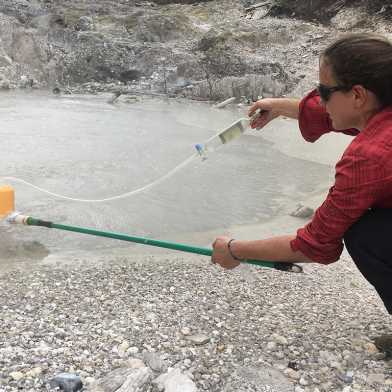 Maren Brehme at work by a pond surrounded by gravel
